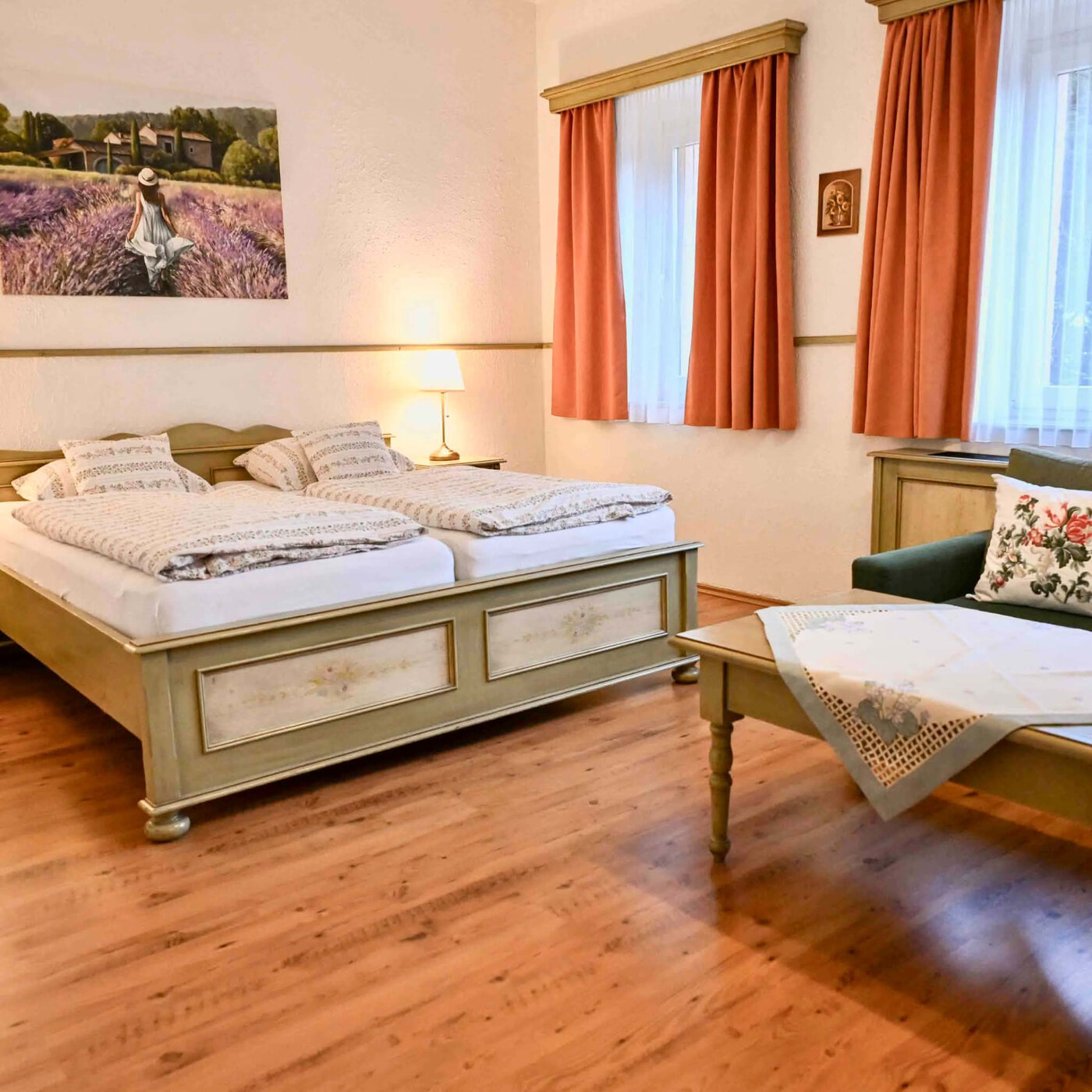 Ložnice apartmánu 2 s dvojlůžkem, zeleným křeslem a obrázkem levandulového pole