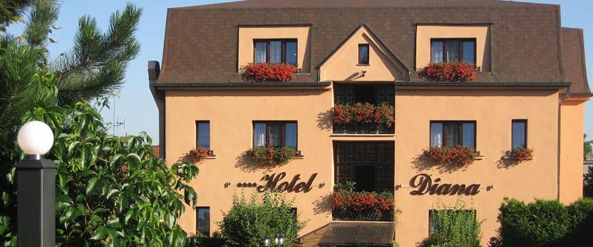 Žlutá fasáda rodinného Hotelu Diana v Praze s květinami v oknech